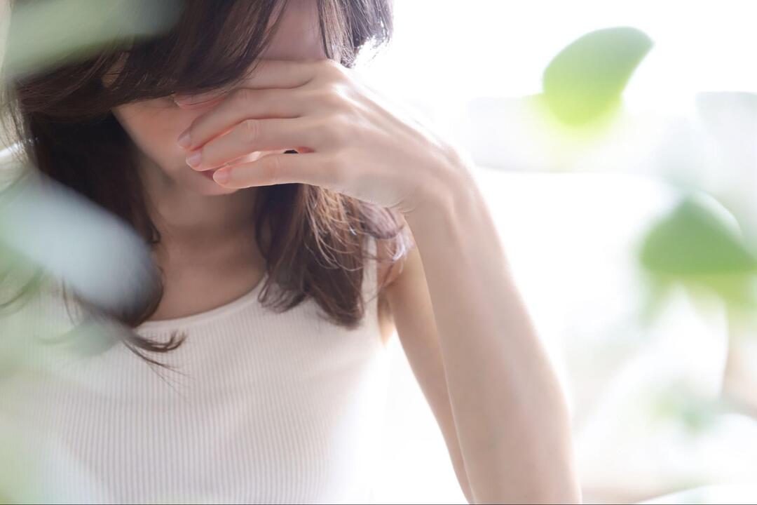 女性が手で目を覆うようにして顔を伏せている様子