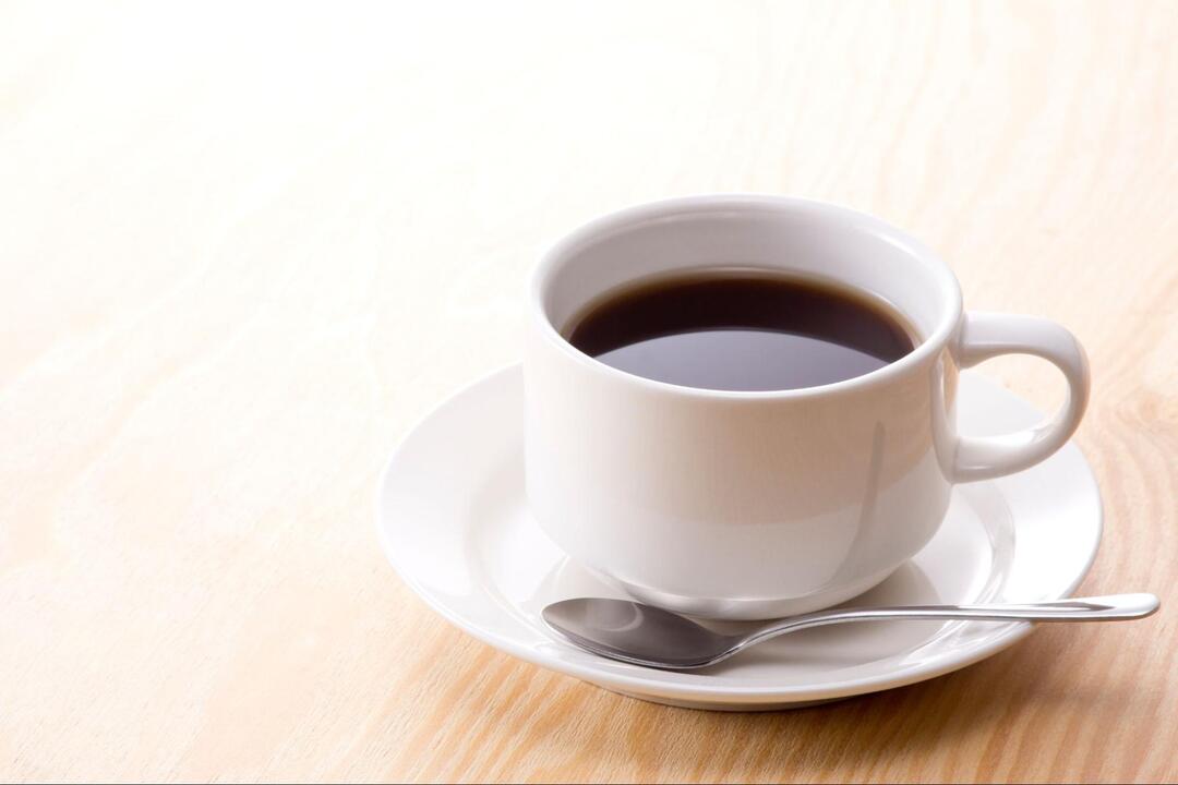 テーブルの上に置かれた白いカップ&ソーサー入りのブラックコーヒー