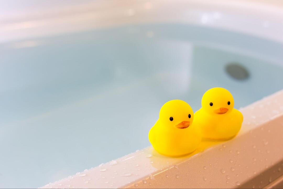 水が張られた浴槽の縁に、2匹並べて置かれた黄色いゴム製のアヒルの玩具