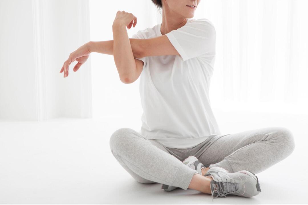床に座って気持ちよさそうにストレッチをしている女性