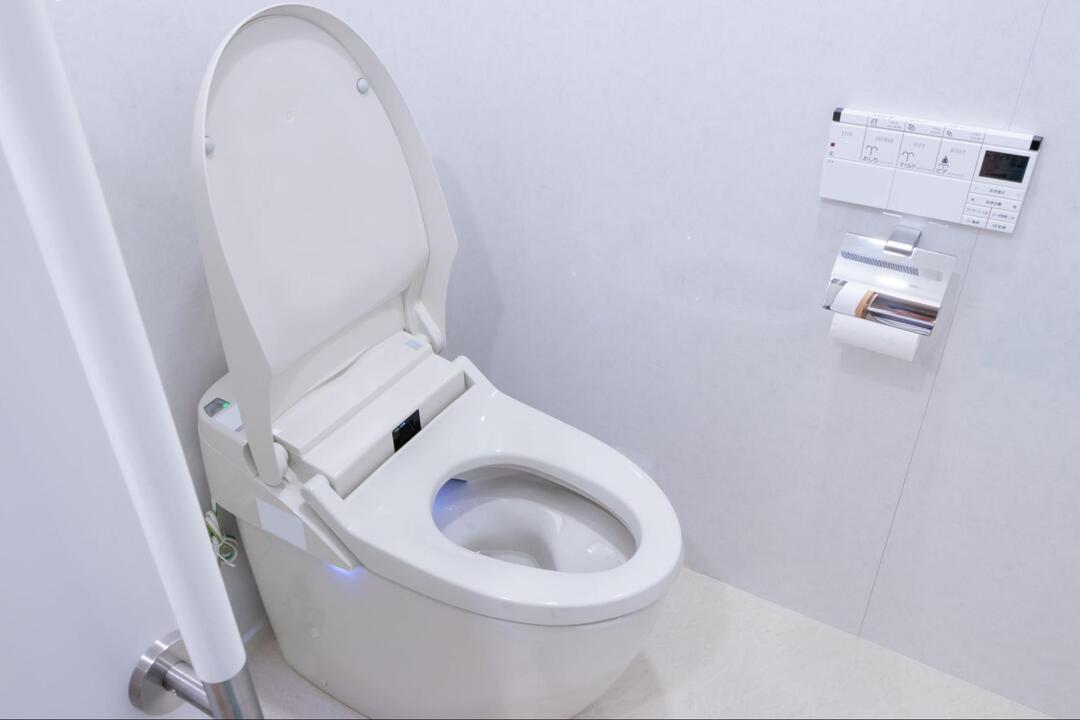 白を基調とした明るく清潔感のある空間に設置された、便座の蓋が開いた状態の洋式トイレ