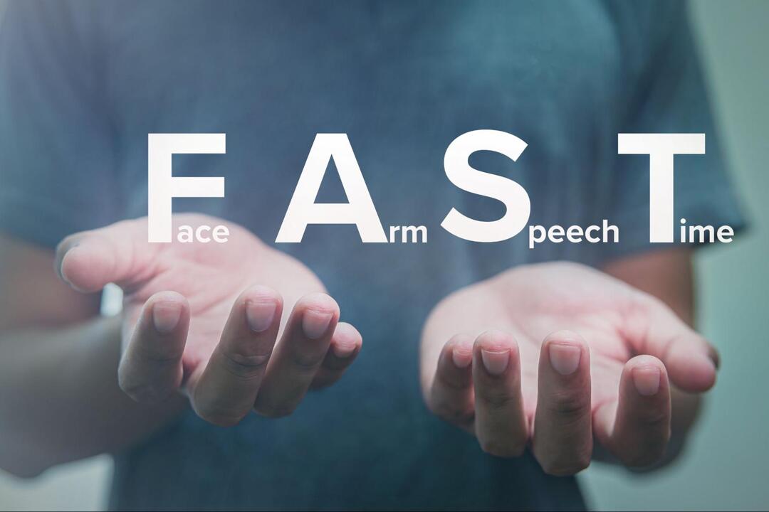 両手のひらのに脳卒中の早期発見の指標である「F A S T（Face, Arm, Speech, Time）」の文字が重ねられたイメージ画像