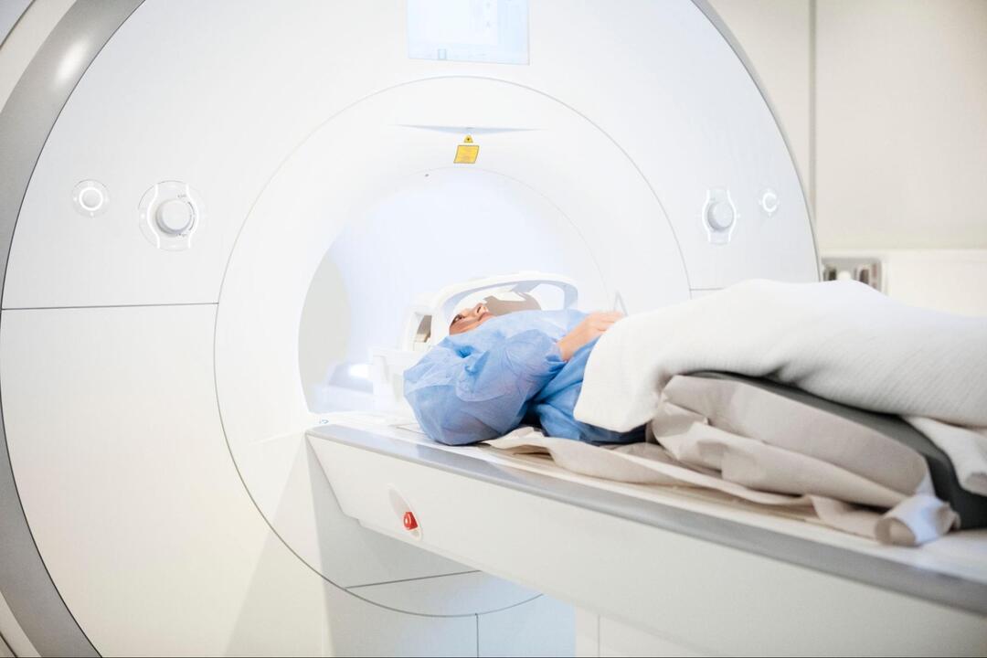医療用MRI装置のベッドに仰向けで横たわり、検査を受けている患者